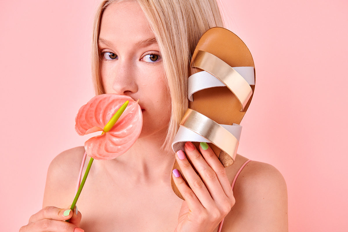 Maki Sandals in gold silver colour delecately placed against the models face.
