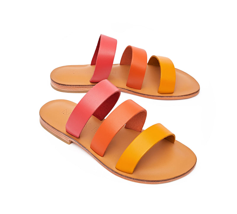 Angled view of the handmade Sky women's slip-on leather sandals in natural tan insole with pomegranate, orange and yellow straps / SUNSET