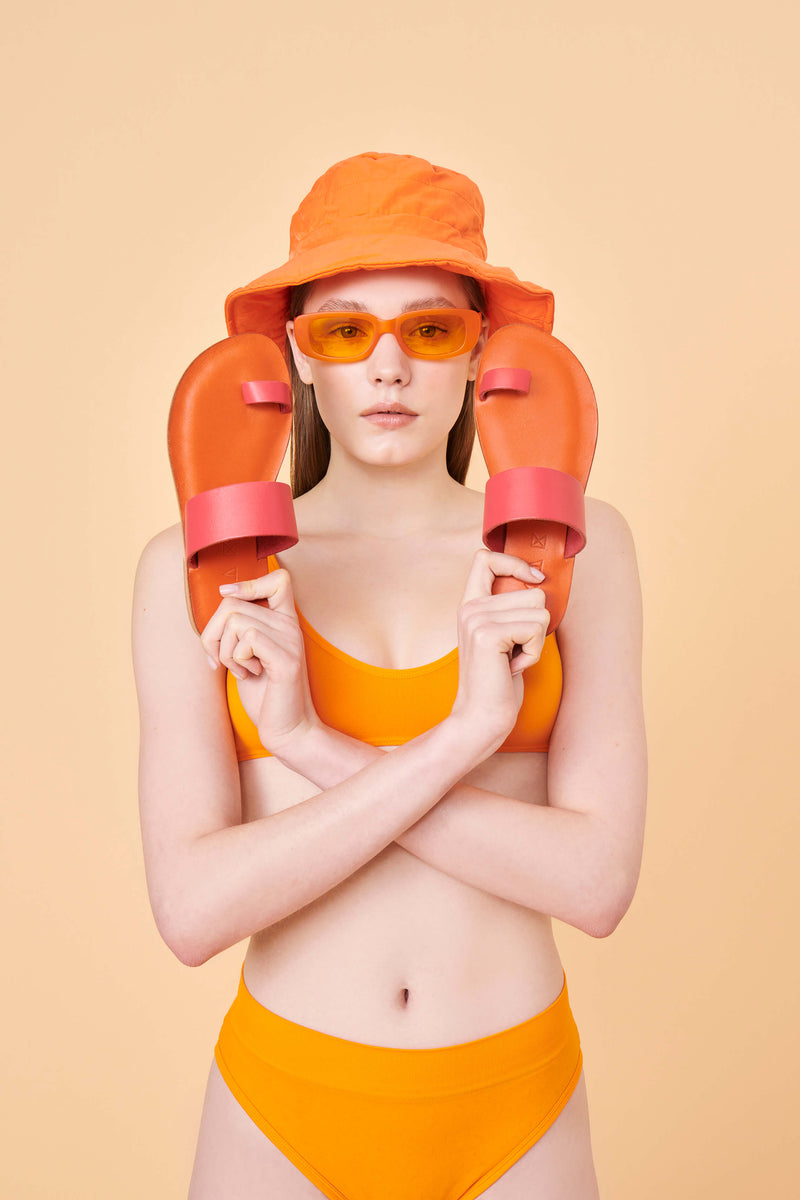 Model wearing the handmade Root women's slip-on leather sandals in pomegranate / POMEGRANATE