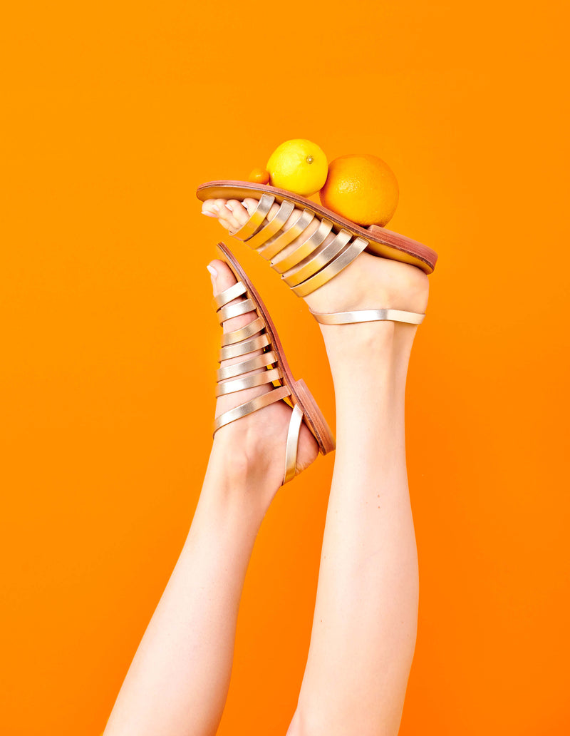 Model wearing the handmade Ray women's slingback leather sandals in natural tan insole with gold straps / GOLD