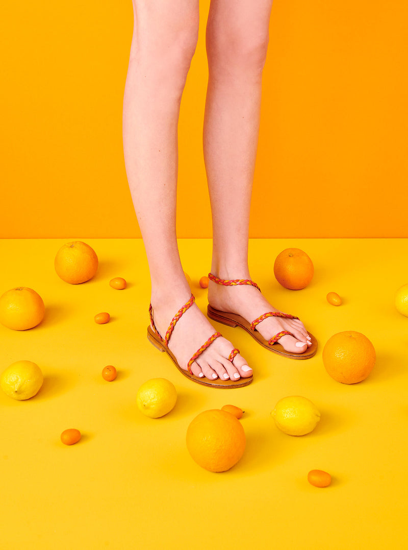 Model wearing the handmade Salt women's braided slingback leather sandals in natural tan insole with pomegranate, orange and yellow straps / SUNSET